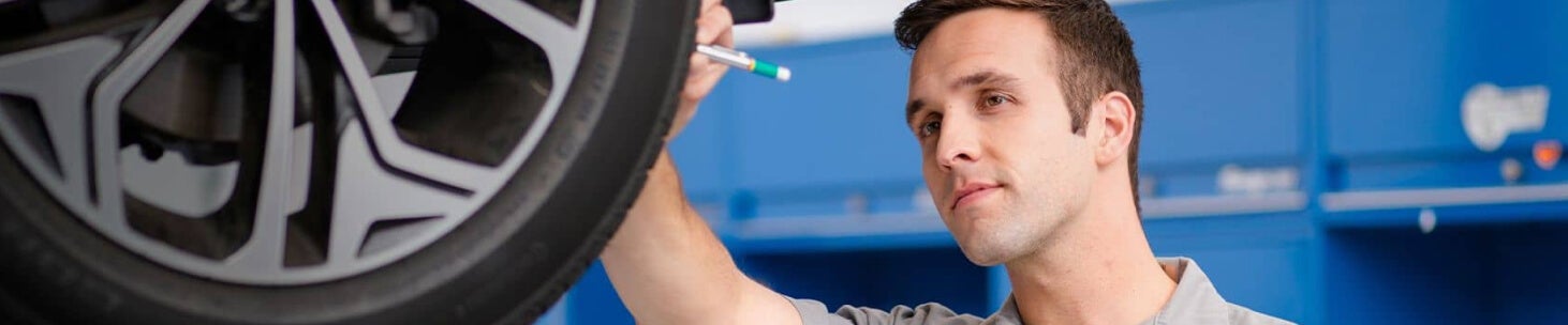 A Hyundai Certified Technicial inspects the tread on a tire.